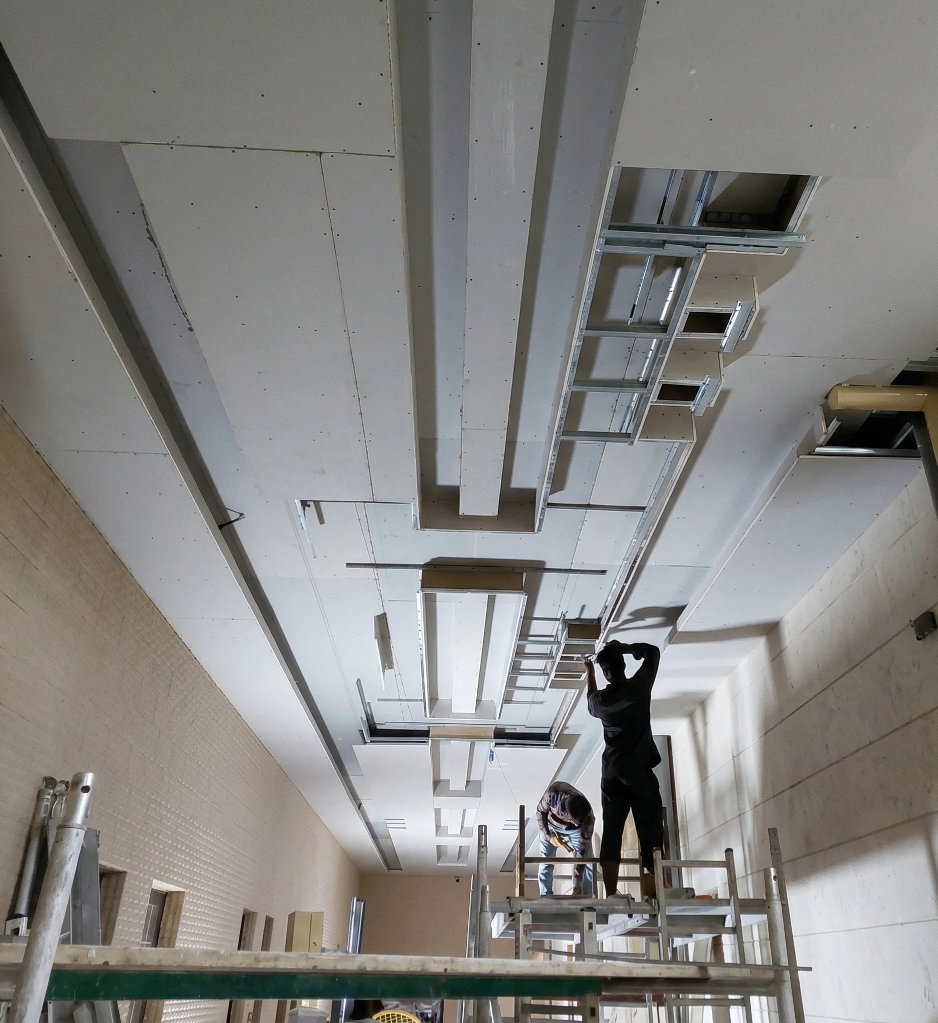 False ceiling gypsum board framework installation workers on scaffolding Dubai