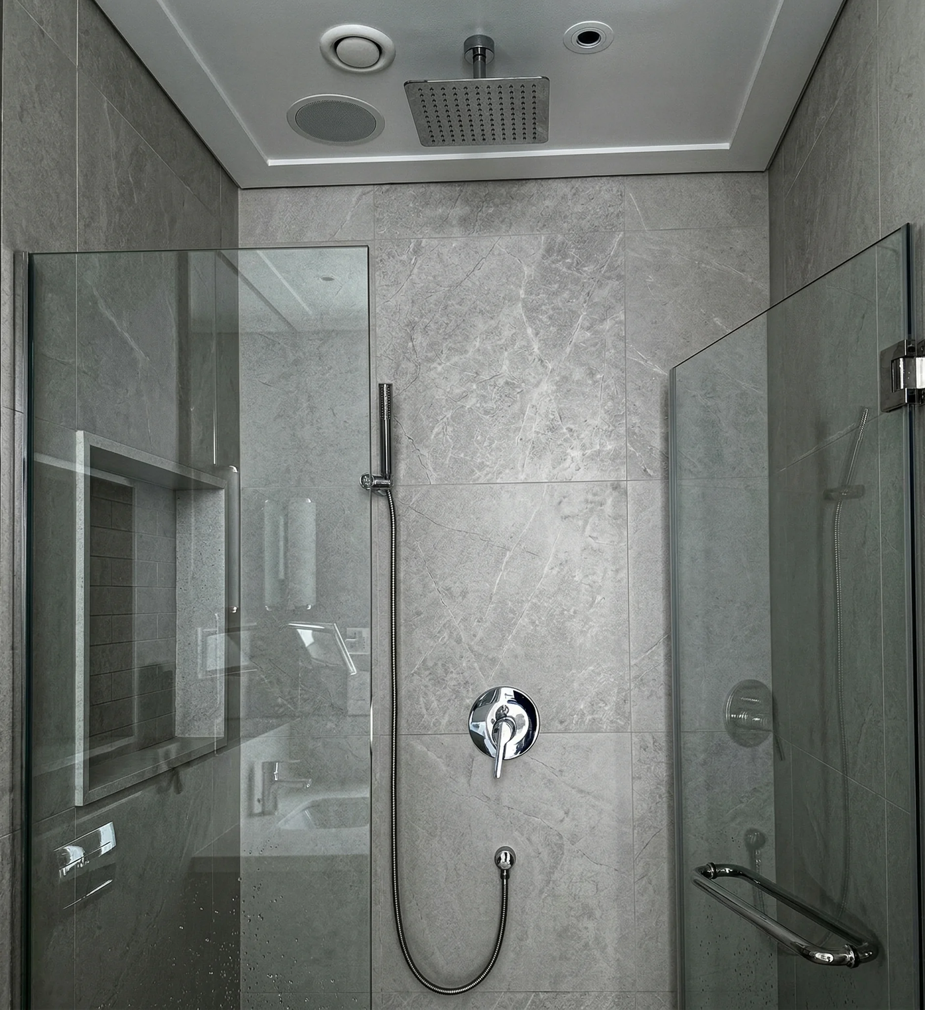 Modern bathroom shower marble tile installation with glass enclosure plumbing Dubai