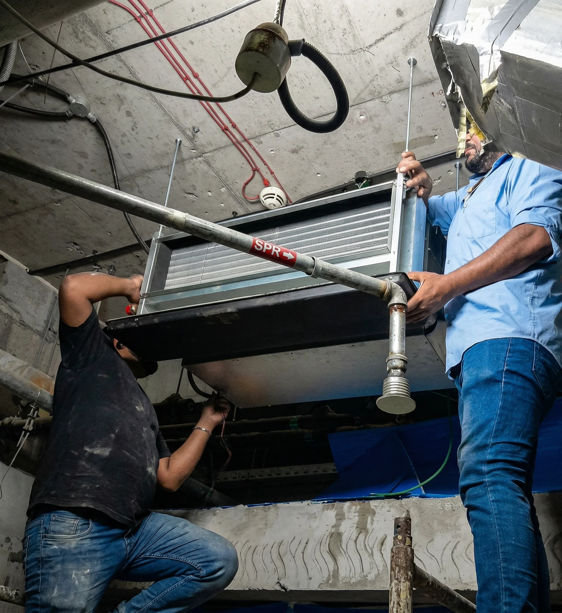 Technicians installing commercial HVAC fan coil unit AC maintenance Dubai